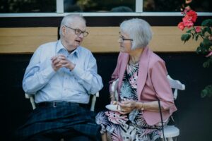 Elderly couple sitting outside talking.